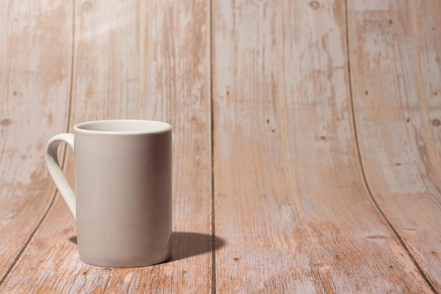 Tazza da caffè bianca liscia su sfondo vintage in legno chiaro