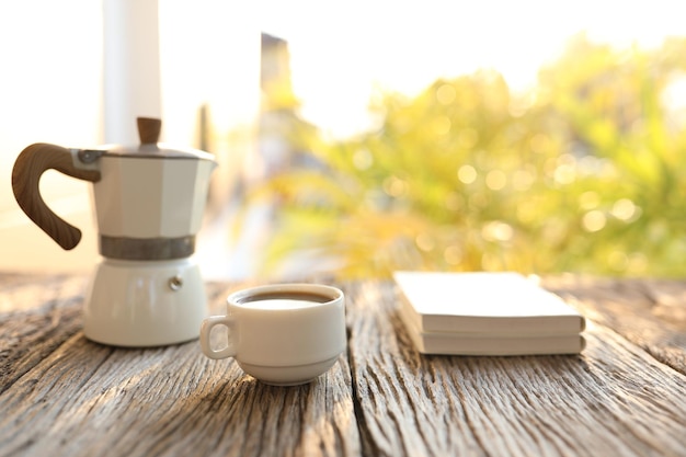 Tazza da caffè e moka bianca e quaderni con luce solare