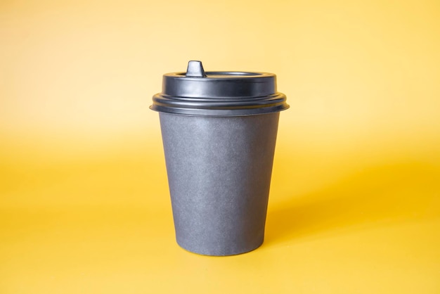 Tazza da caffè in carta nera su sfondo giallo Spazio vuoto per testo e design su una tazza di caffè modulo per il nome del caffè o dell'azienda o della caffetteria
