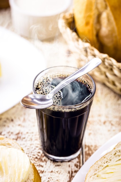 Tazza da caffè nera e dolce con cucchiaio di metallo, bevanda calda tipica del Brasile, servita a colazione