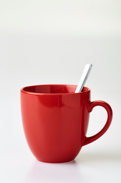 Tazza da caffè rossa e cucchiaio sfondo bianco vuoto.