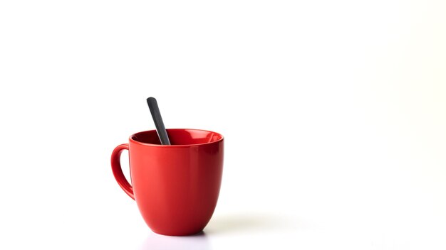 Tazza da caffè rossa e cucchiaio sfondo bianco vuoto.