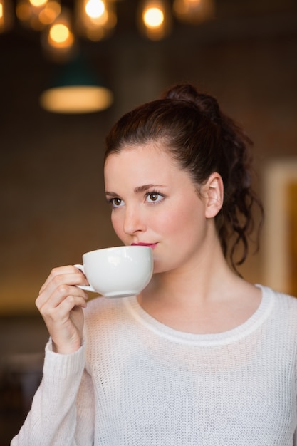 Tazza da caffè sorseggiante graziosa del brunette