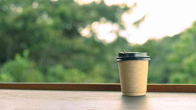 Tazza da caffè usa e getta su tavola di legno con sfondo naturale.