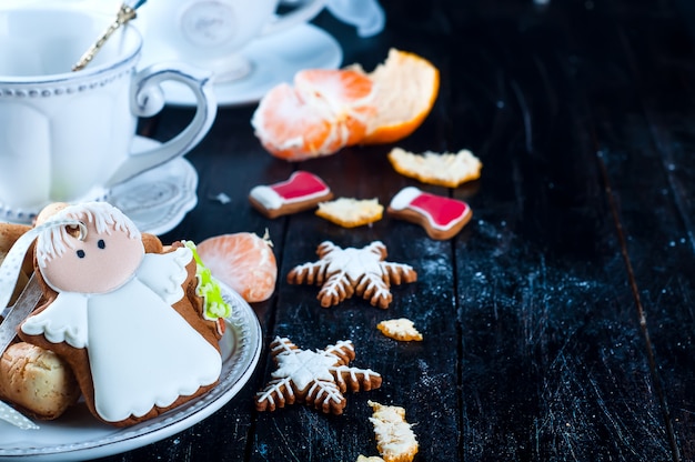 Tazza da tè con angelo tè e biscotti, tangerineon un tavolo nero