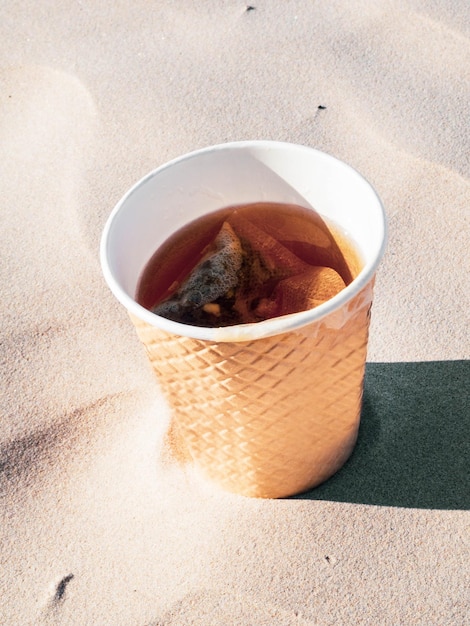 Tazza da tè da asporto con tè su sfondo di sabbia di mare