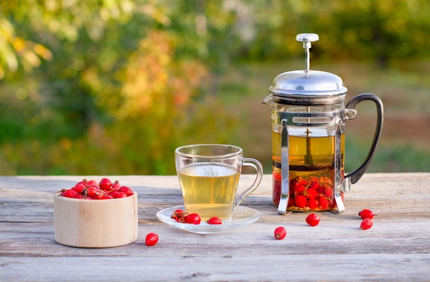 Tazza da tè di vetro con una teiera e bacche rosse