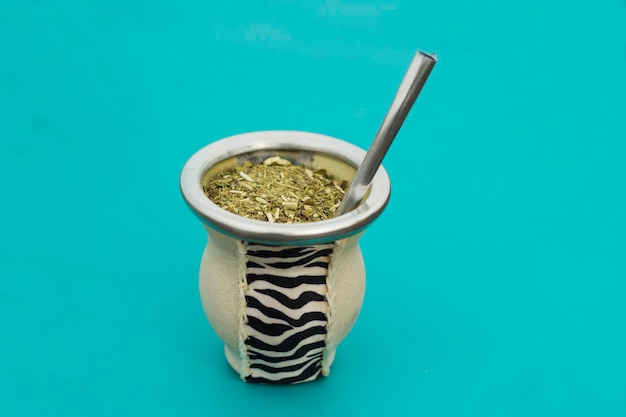 Tazza da tè Yerba Mate con cannuccia metallica bombilla che funge da sfondo blu del tè