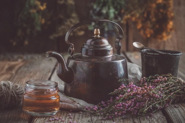 Tazza da teiera vintage di tisane sane, vasetto di miele, mazzo di erica e fasci di erbe medicinali