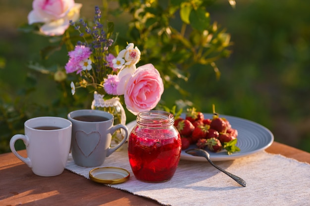 Tazza da the con le rose rosa su una tavola di legno di mattina