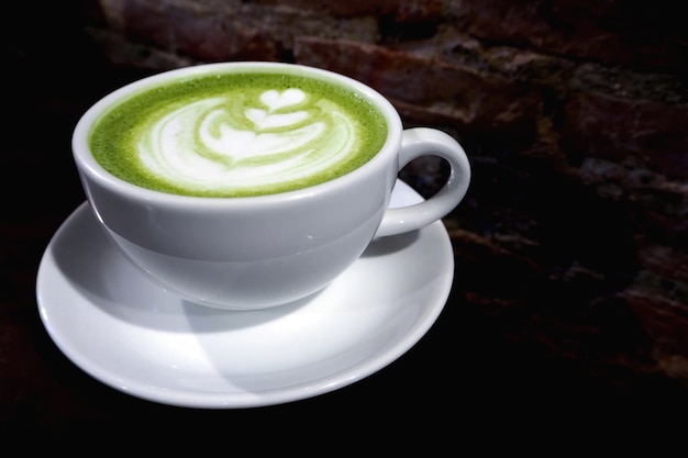 Tazza del latte del tè verde di Matcha sul fondo del muro di mattoni
