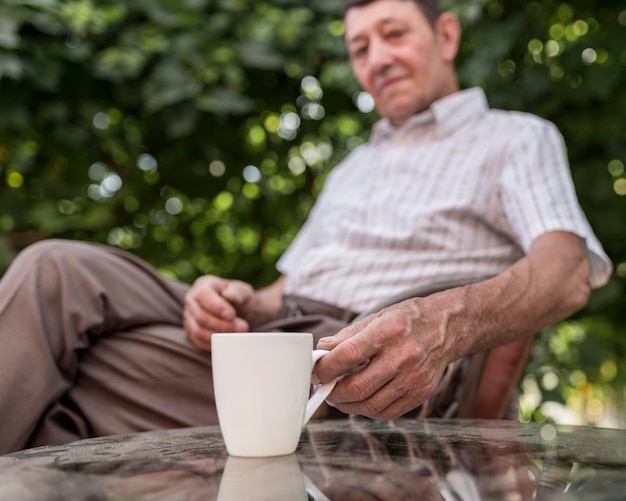 Tazza della holding dell'uomo vago colpo medio