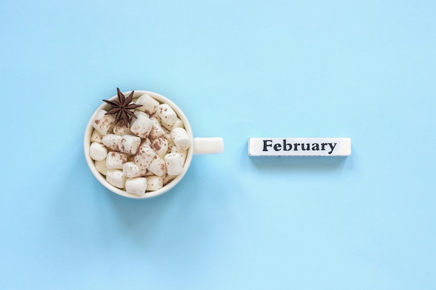 Tazza delle caramelle gommosa e molle del cacao e calendario febbraio su fondo blu