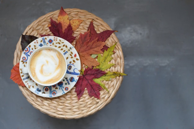 Tazza di Autumn Coffe Foglie di acero Tavolo in vimini Stagione autunnale Confortevole casa Comfort piano copyspace copyspace Vista dall'alto