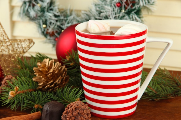 Tazza di cacao caldo con cioccolatini e decorazioni natalizie sul tavolo su fondo di legno