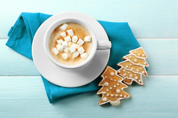 Tazza di cacao caldo con marshmallow, biscotti e tovagliolo sul tavolo blu