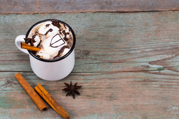 Tazza di cacao fatta in casa con cannella Marshmallow e anice stellato su sfondo di legno con spazio di copia.