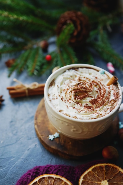 Tazza di cacao o cioccolata calda con crema alla cannella arance secche e abete su tavola di pietra scura Decorazione natalizia accogliente casa invernale sfondo fuoco selettivo