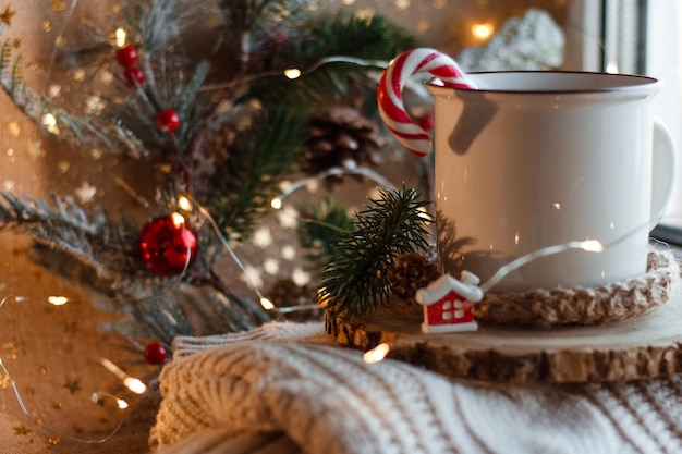 Tazza di cacao su supporto in legno e maglione lavorato a maglia