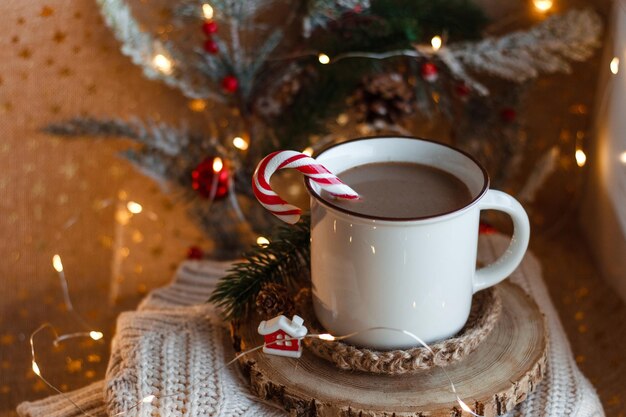 Tazza di cacao su supporto in legno e maglione lavorato a maglia