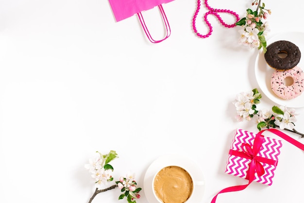 Tazza di caffè al mattino ciambelle dolci una confezione regalo con un sacchetto di carta e fiori di mela su un tavolo bianco in cima a una meravigliosa colazione Flat lady style