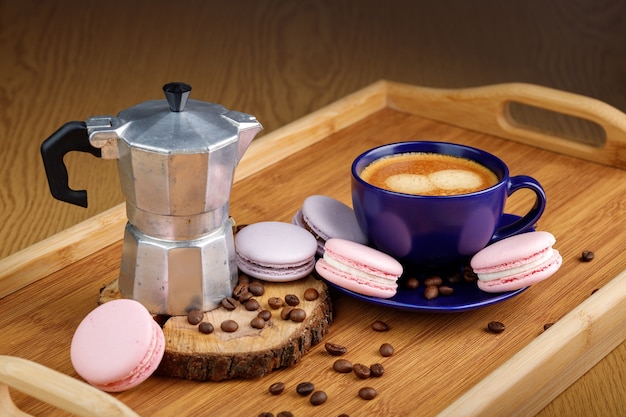 Tazza di caffè amaretti e chicchi di caffè su un piatto e macchina per il caffè geyser su un vassoio di legno