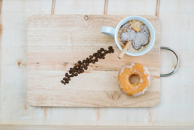 tazza di caffè aromatico con la ciambella su fondo di legno