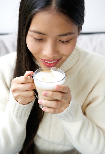 Tazza di caffè bevente della giovane donna asiatica attraente