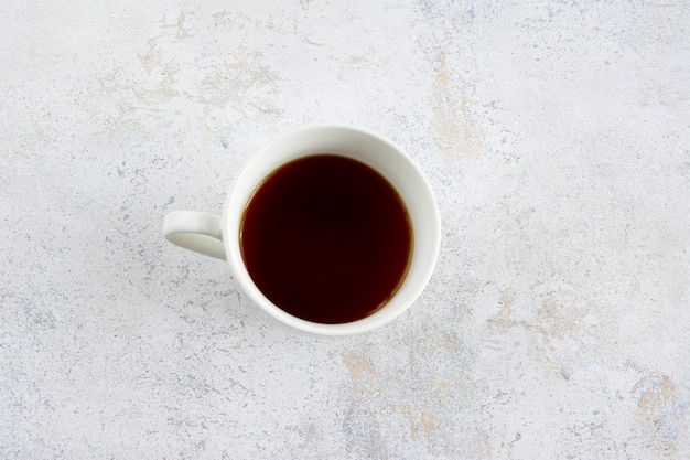 tazza di caffè bianca isolata su sfondo concreto, vista dall'alto