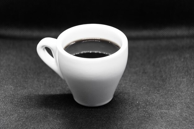 Tazza di caffè bianca su sfondo nero.