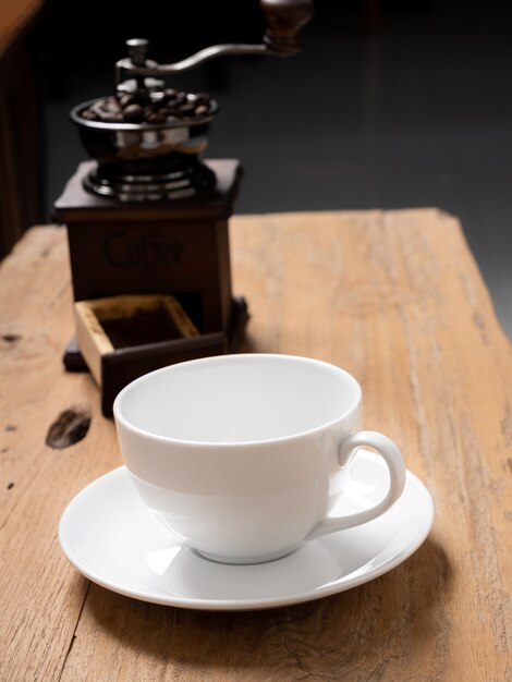 Tazza di caffè bianco e macinino da caffè su fondo di legno del grunge