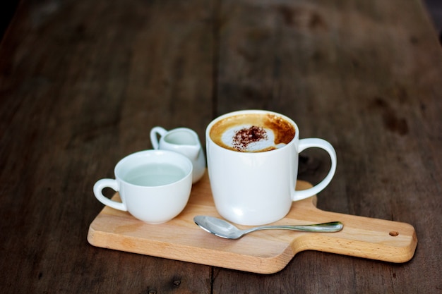 Tazza di caffè bianco posizionata su legno.