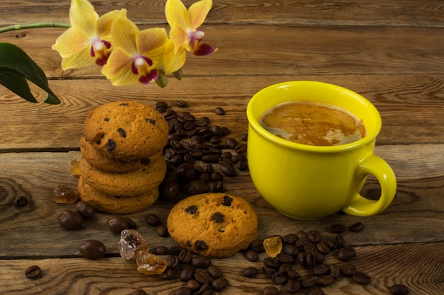 Tazza di caffè, biscotti e orchidea gialla