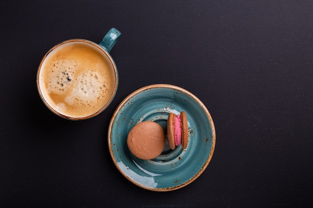 Tazza di caffè blu e amaretti sul tavolo di legno scuro