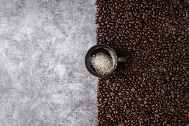 Tazza di caffè calda con chicchi di caffè sul fondo della parete del cemento.