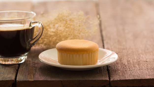 Tazza di caffè caldo con il dolce del burro sulla tavola il giorno di inverno, tonalità d&#39;annata