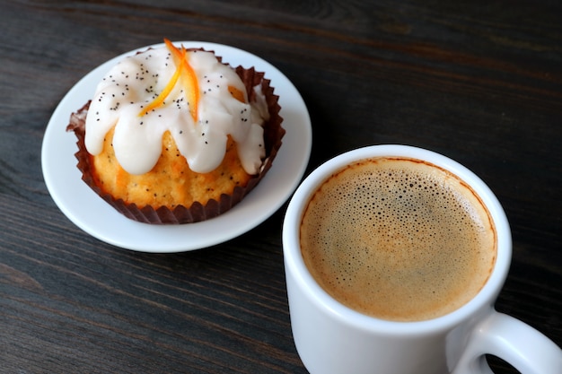 Tazza di caffè caldo con Poppy Seed Yogurt Cake arancione servita sul tavolo di legno