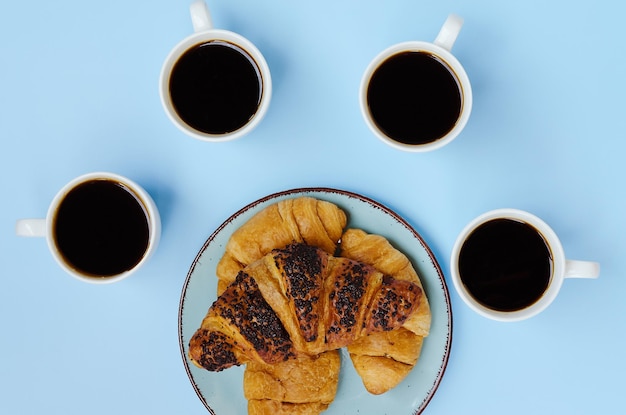 tazza di caffè caldo, croissant dolce e bouquet di lavanda su sfondo blu. Vista dall'alto, copia spazio