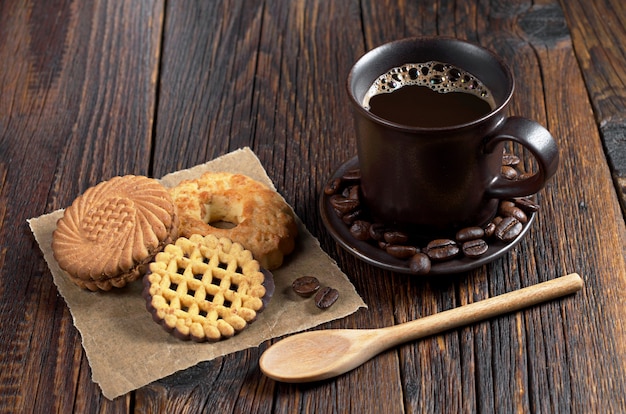 Tazza di caffè caldo e biscotti diversi sul tavolo di legno scuro