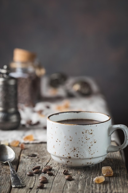 Tazza di caffè caldo e chicchi di caffè sulla tavola di legno, stile rustico