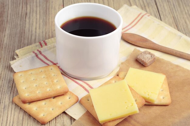 Tazza di caffè caldo e cracker con formaggio e su tavola rustica