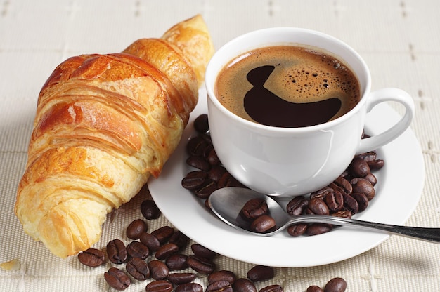 Tazza di caffè caldo e croissant sulla tovaglia nascosta del tavolo