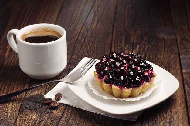 Tazza di caffè caldo e torta con ribes nero sul tavolo di legno scuro
