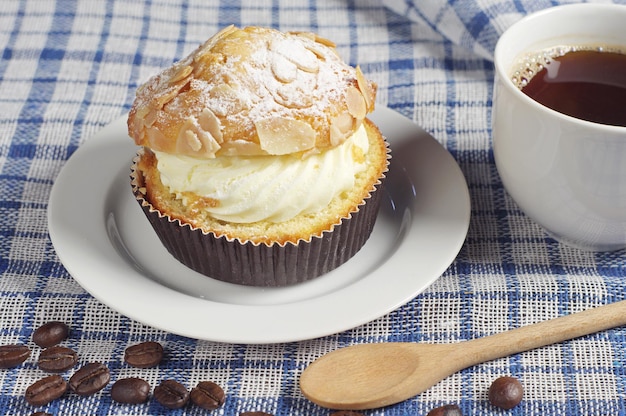 Tazza di caffè caldo e torta cremosa con noci sulla tovaglia blu