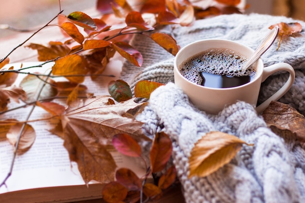 Tazza di caffè caldo fumante e un vecchio libro sul tavolo di legno