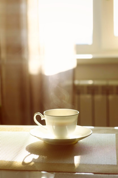 Tazza di caffè caldo fumante in una mattina di sole sul tavolo della cucina