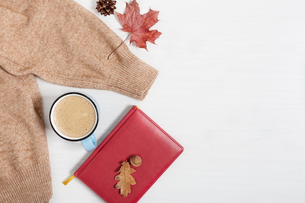 Tazza di caffè caldo maglione autunnale e libro su sfondo bianco di legno Sfondo autunnale