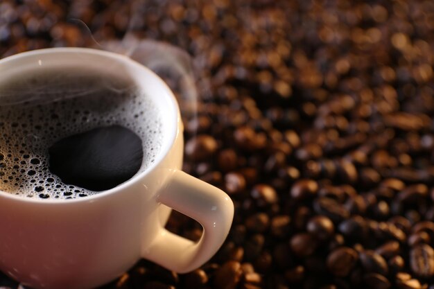 Tazza di caffè caldo su sfondo di chicchi di caffè