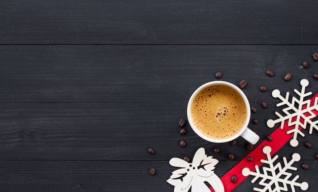 Tazza di caffè caldo su superficie di legno nera nel periodo natalizio