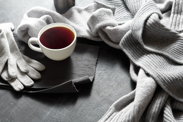 Tazza di caffè caldo su un tavolo nero, foto ravvicinata maglione caldo con tazza, concetto di mattina invernale, vista dall'alto